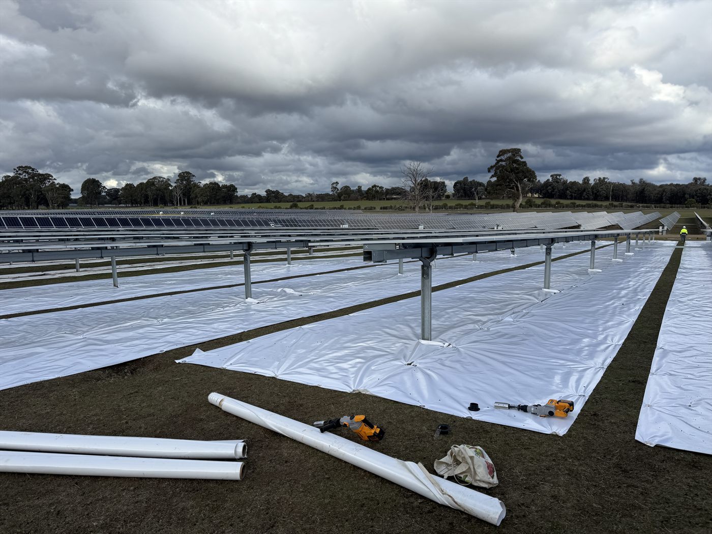 Elevated perspective of many mat-covered tracker rows during installation at an Australian site.