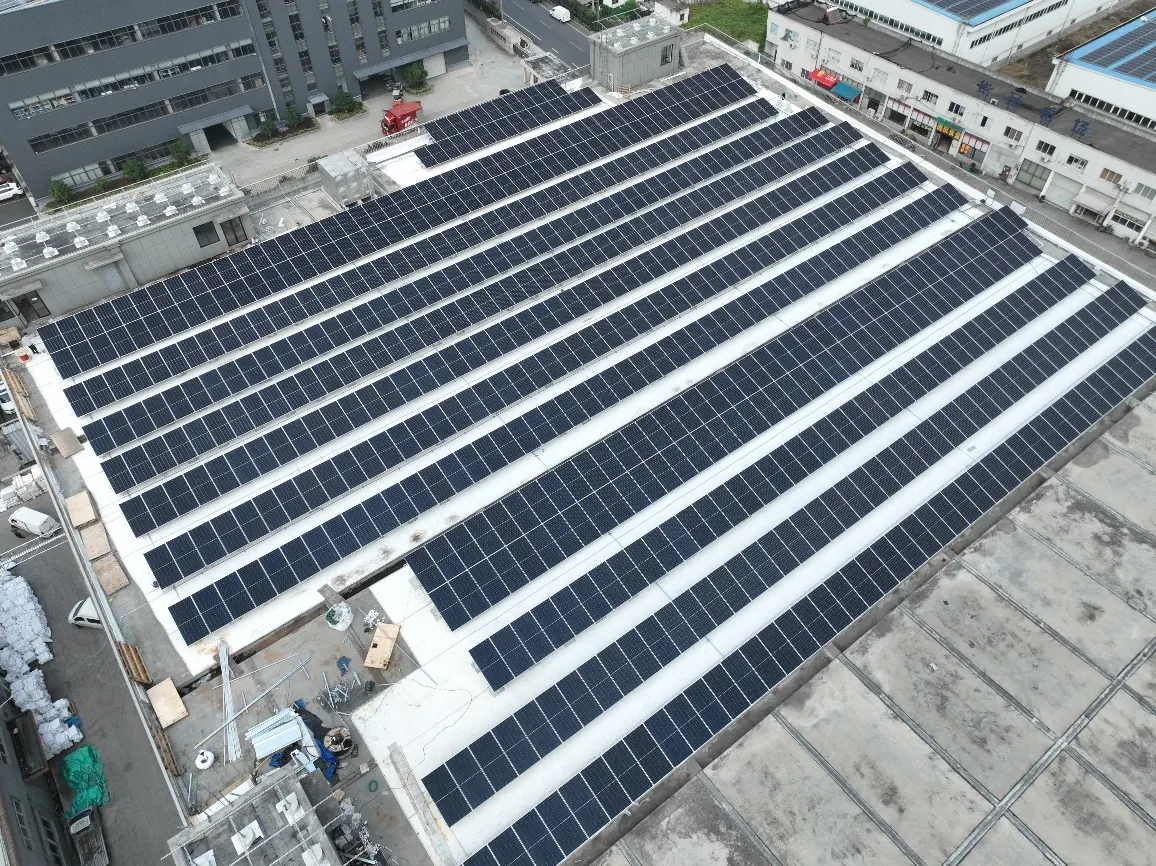 Aerial view of a factory roof covered in bifacial modules, with white reflective matting between every row.