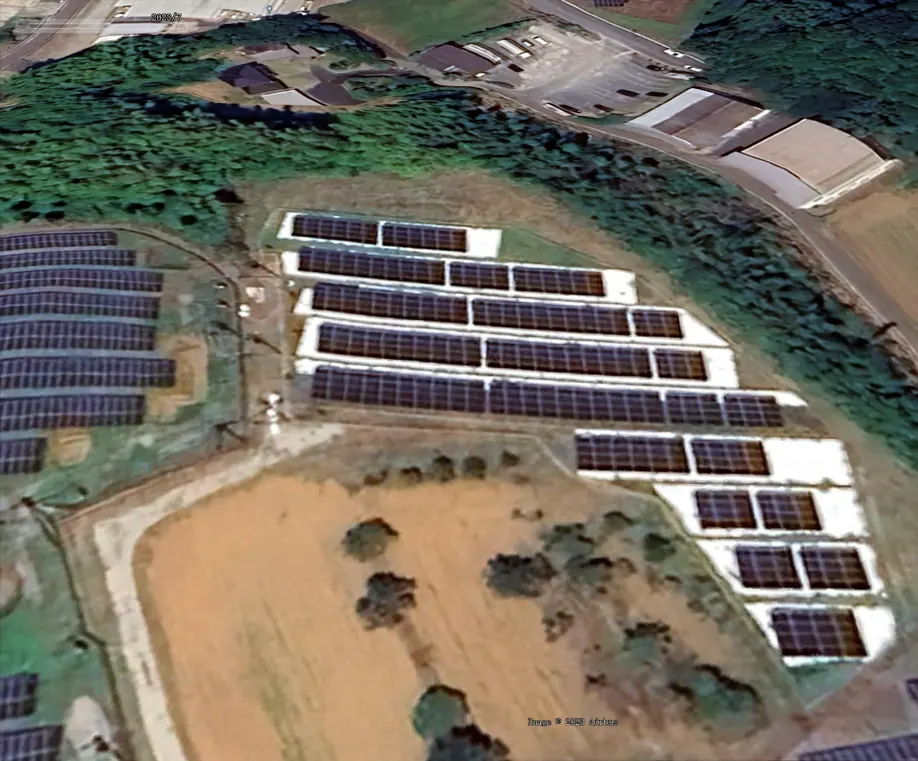 Aerial view of a hillside solar array where each row sits on a bright white reflective mat.